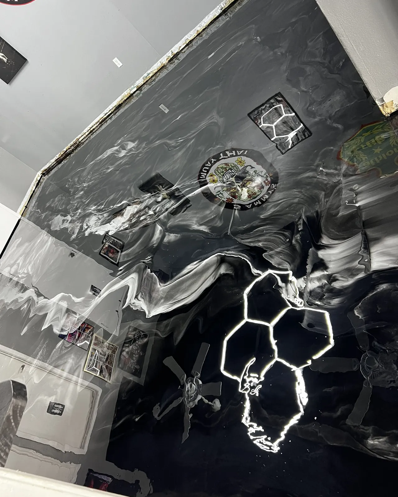 Black and white metallic epoxy floor at Sammy's Muay Thai, gloss deep enough to mirror the hex lights