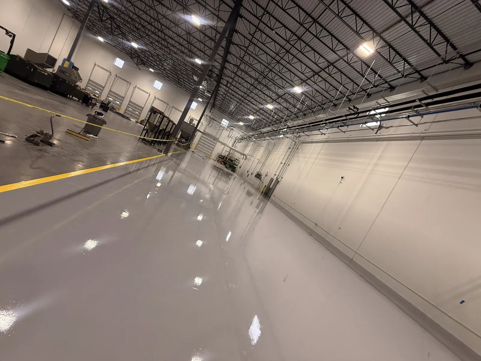 Warehouse floor in solid grey epoxy with a yellow safety line running down it